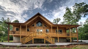 A large wooden cabin with a central staircase, multiple balconies, and a covered porch area.