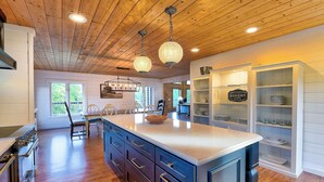 Une cuisine spacieuse avec un plancher en bois, un grand îlot central et des luminaires suspendus.