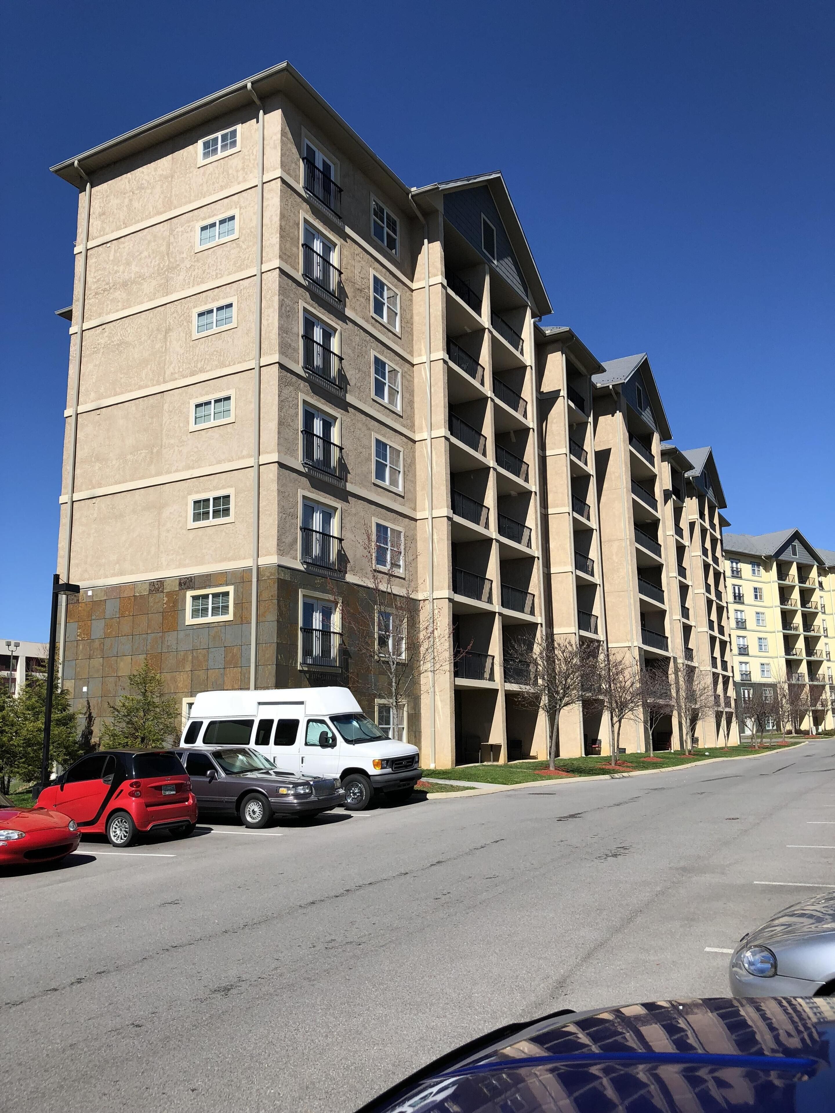 A multi-story apartment building with balconies and a parking lot.