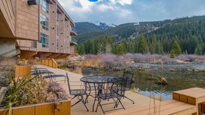Un bâtiment moderne doté d’une terrasse offrant une vue sur une rivière et des collines boisées.