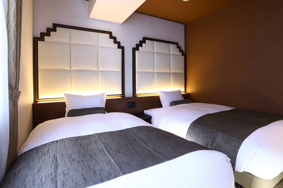 Une chambre d’hôtel avec deux lits, un grand miroir et un design moderne.