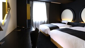 Een moderne hotelkamer met twee bedden, een bureau en een grote spiegel.