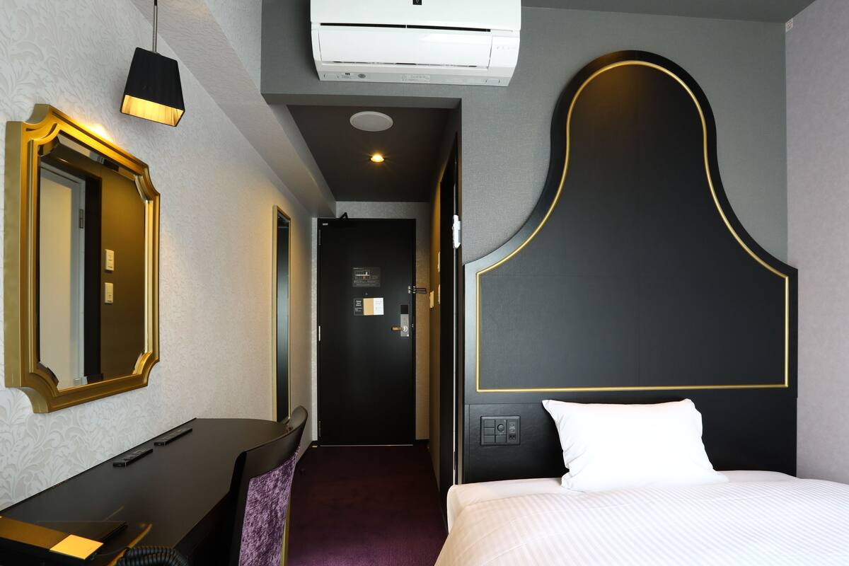 Une chambre d’hôtel équipée d’un lit, d’un bureau, d’une chaise, d’un miroir et d’un appareil de climatisation.
