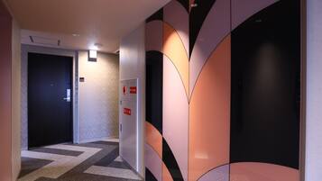 Een gang met een kamerbreed tapijt, een deur en een wand met abstracte designs.