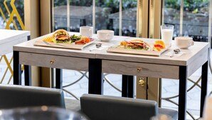 Een eettafel met twee borden eten, twee witte bekers en een glas melk.
