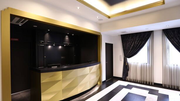 Een moderne keuken met een zwart aanrecht, gouden accenten en een geometrisch patroon op de achterwand.