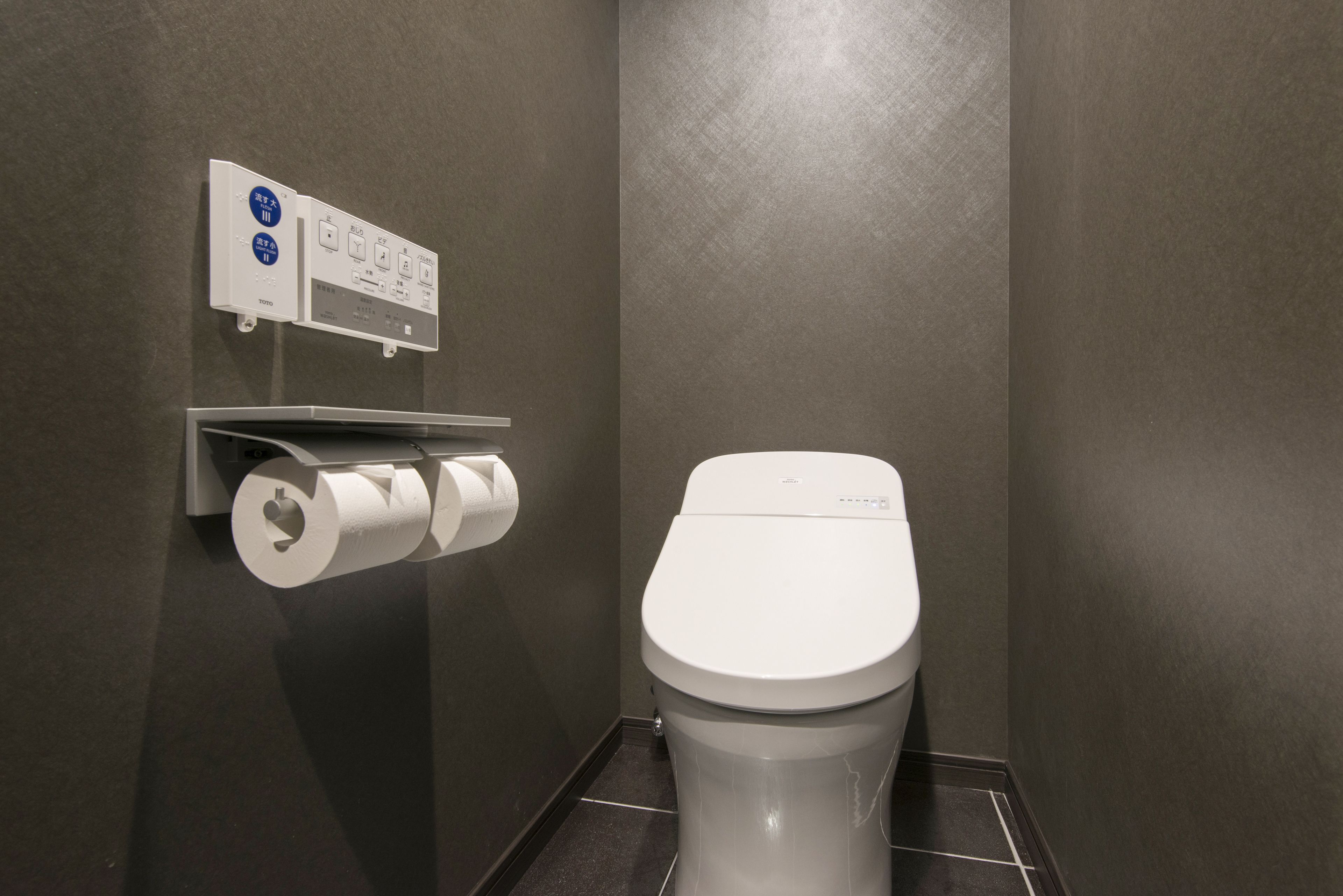 Un baño moderno con inodoro, dispensador de toallas de papel y secador de manos.