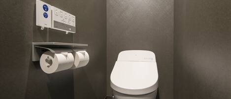 Un baño moderno con inodoro, dispensador de toallas de papel y secador de manos.