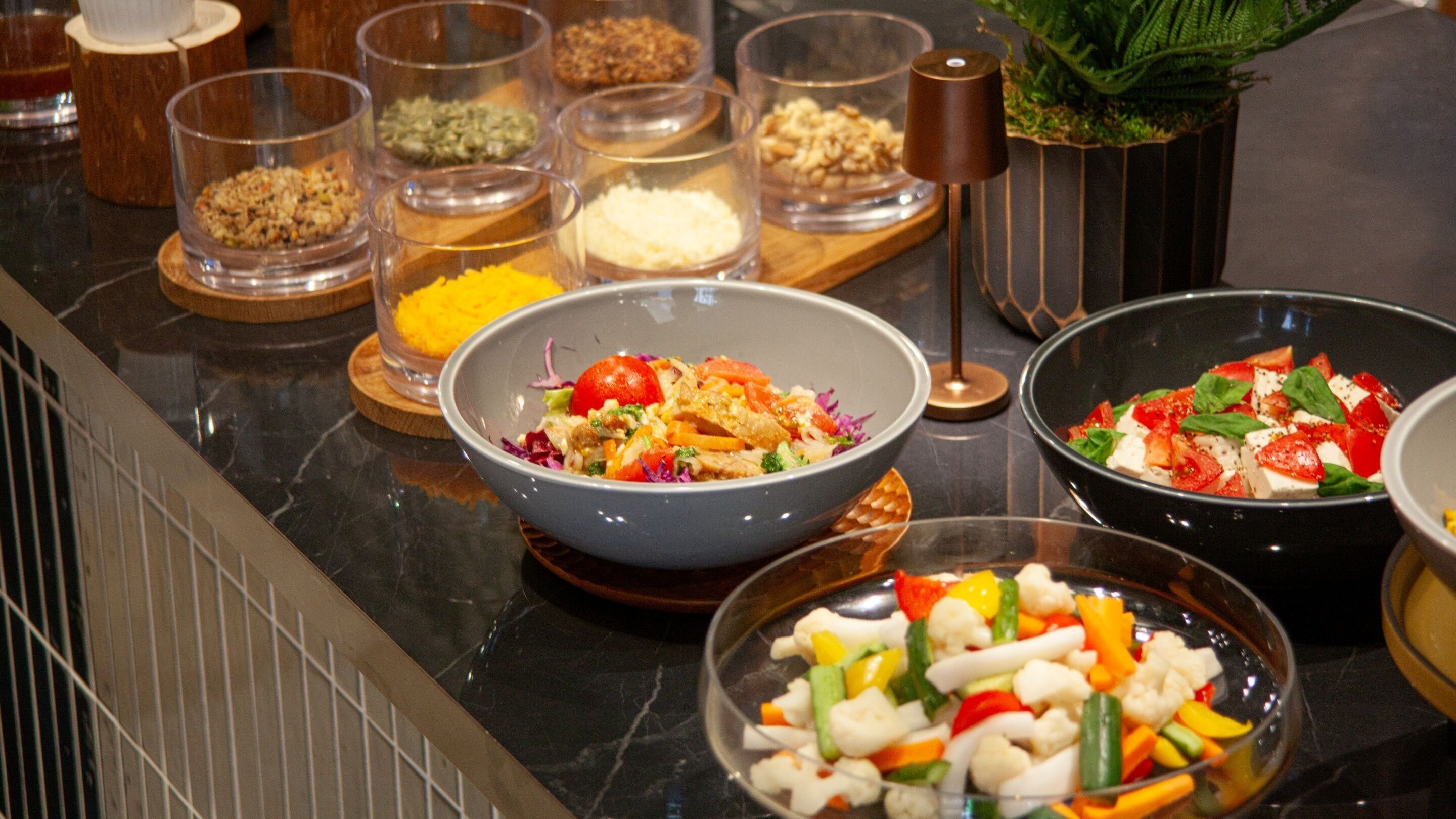 A buffet with various dishes, including salads and a bowl of mixed vegetables.