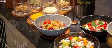 A buffet with various dishes, including salads and a bowl of mixed vegetables.