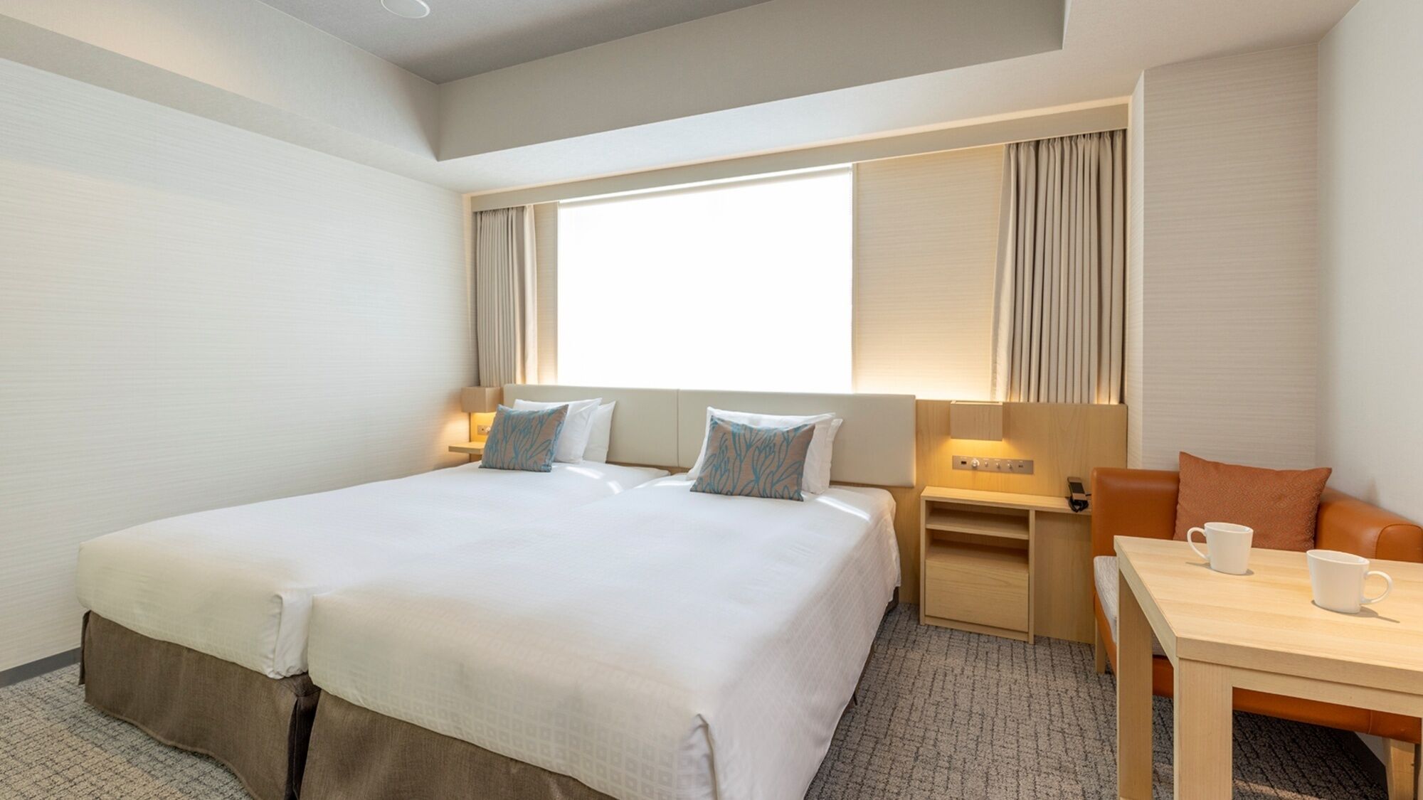 A hotel room with a large bed, bedside tables, a desk, and a chair.