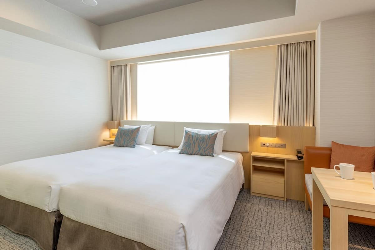 Hotellihuone, jossa on suuri sänky, yöpöydät, työpöytä ja tuoli.