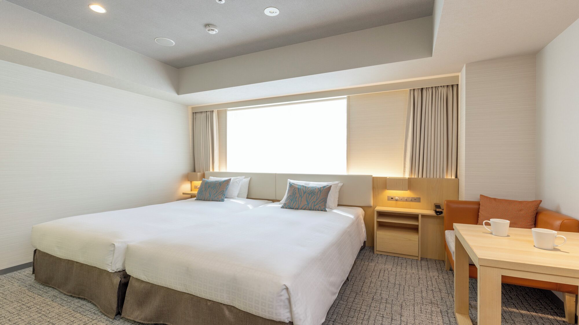 A hotel room with a large bed, bedside tables, a desk, and a chair.