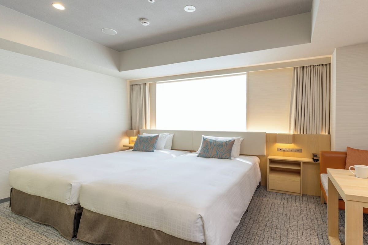 Une chambre d’hôtel avec un grand lit, des tables de chevet, un bureau et une chaise.