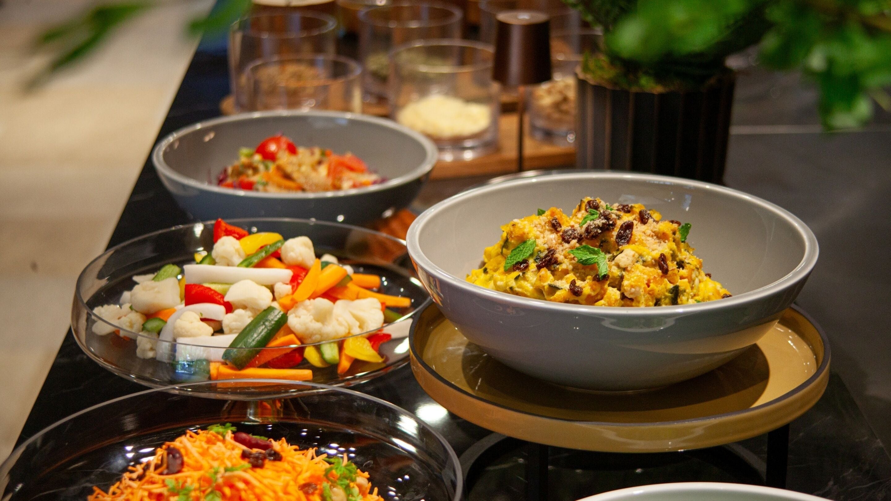 A table with various dishes, including a bowl of mixed vegetables and another with a yellow dish.