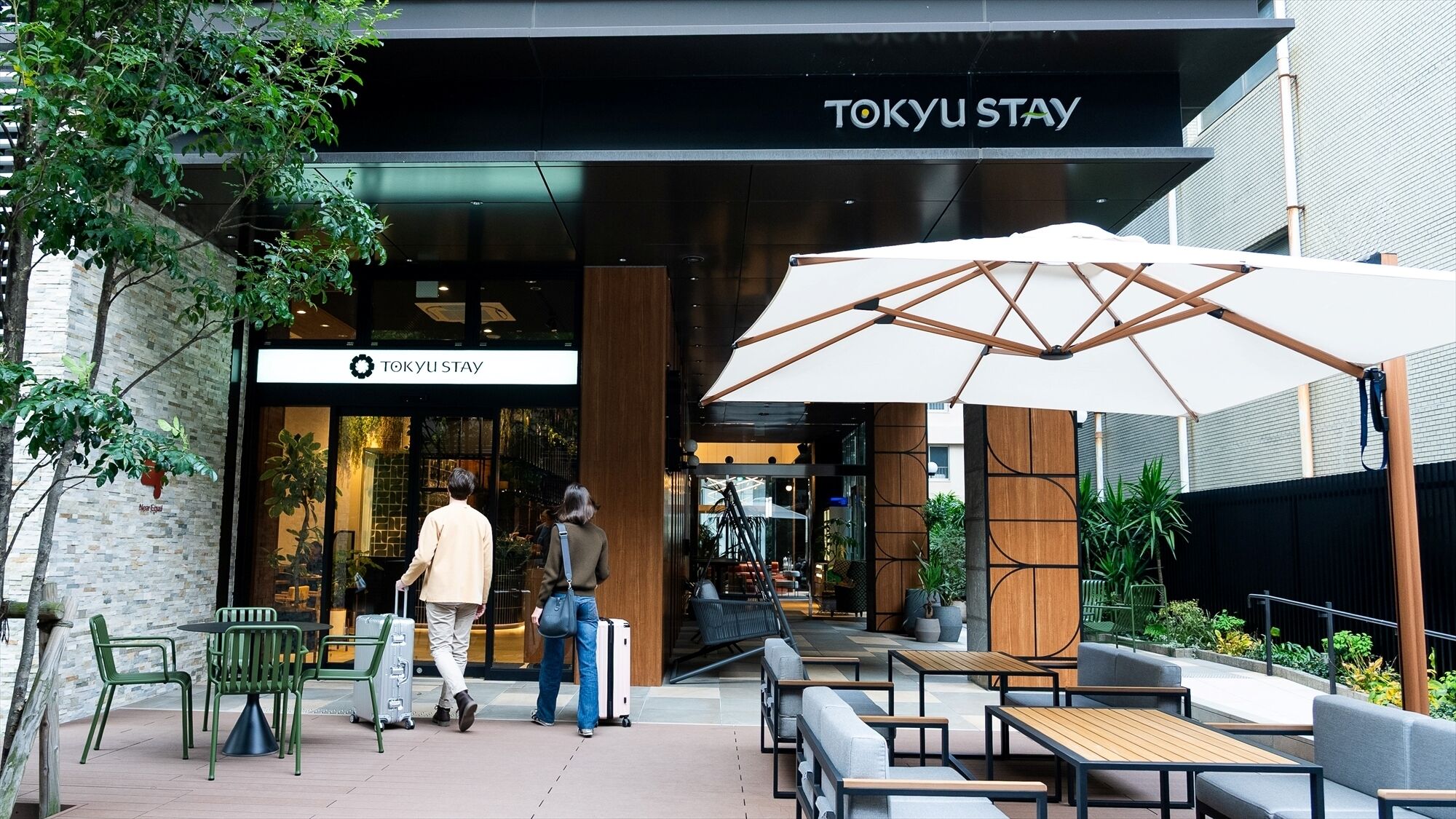A Tokyo Stay hotel entrance with outdoor seating and a covered area.