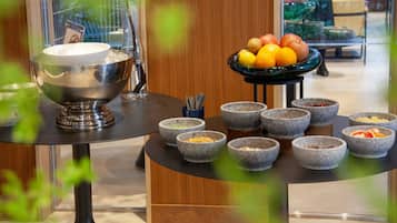 A breakfast setup with a bowl of fruit and several stone bowls on a table.