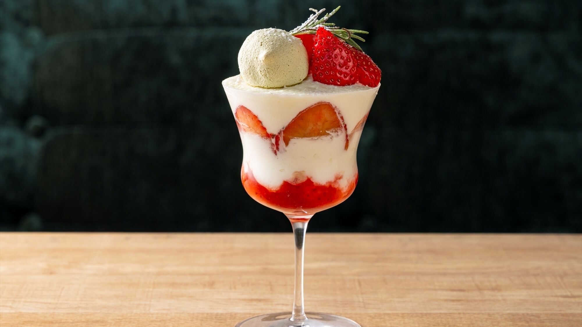 A dessert in a glass with strawberries and a scoop of ice cream on top.
