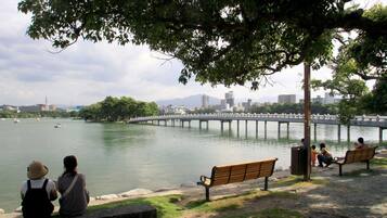 Un parque junto al río con bancos y un puente.