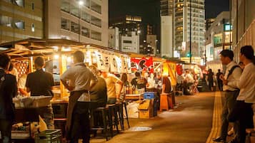 A bustling street food market at night with food stalls and people dining.
