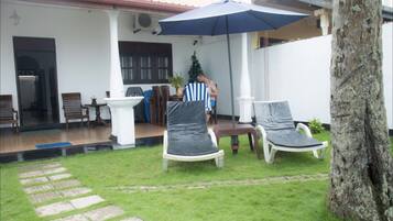 A patio area with two lounge chairs, a small table, and a covered seating area with an umbrella.