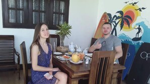 Uma sala de jantar com cadeiras de madeira e uma mesa posta com pratos, bebida e uma planta.