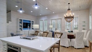 Una cocina amplia con una isla central, suelo de madera y un candelabro.