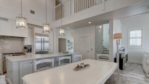 Una cocina amplia con una isla grande, electrodomésticos de acero inoxidable e iluminación colgante.