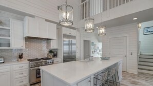 Una cocina moderna con armarios blancos, electrodomésticos de acero inoxidable y una isla grande con taburetes de bar.