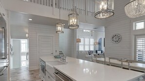 Una cocina amplia con una isla grande, luces colgantes y vista al área de comedor.