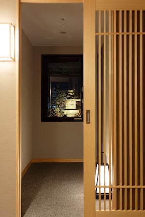 Un pasillo con una puerta de madera que da a una habitación con un ventanal grande.