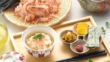 A wooden tray with a bowl of rice, pickled vegetables, and a small dish of fish.
