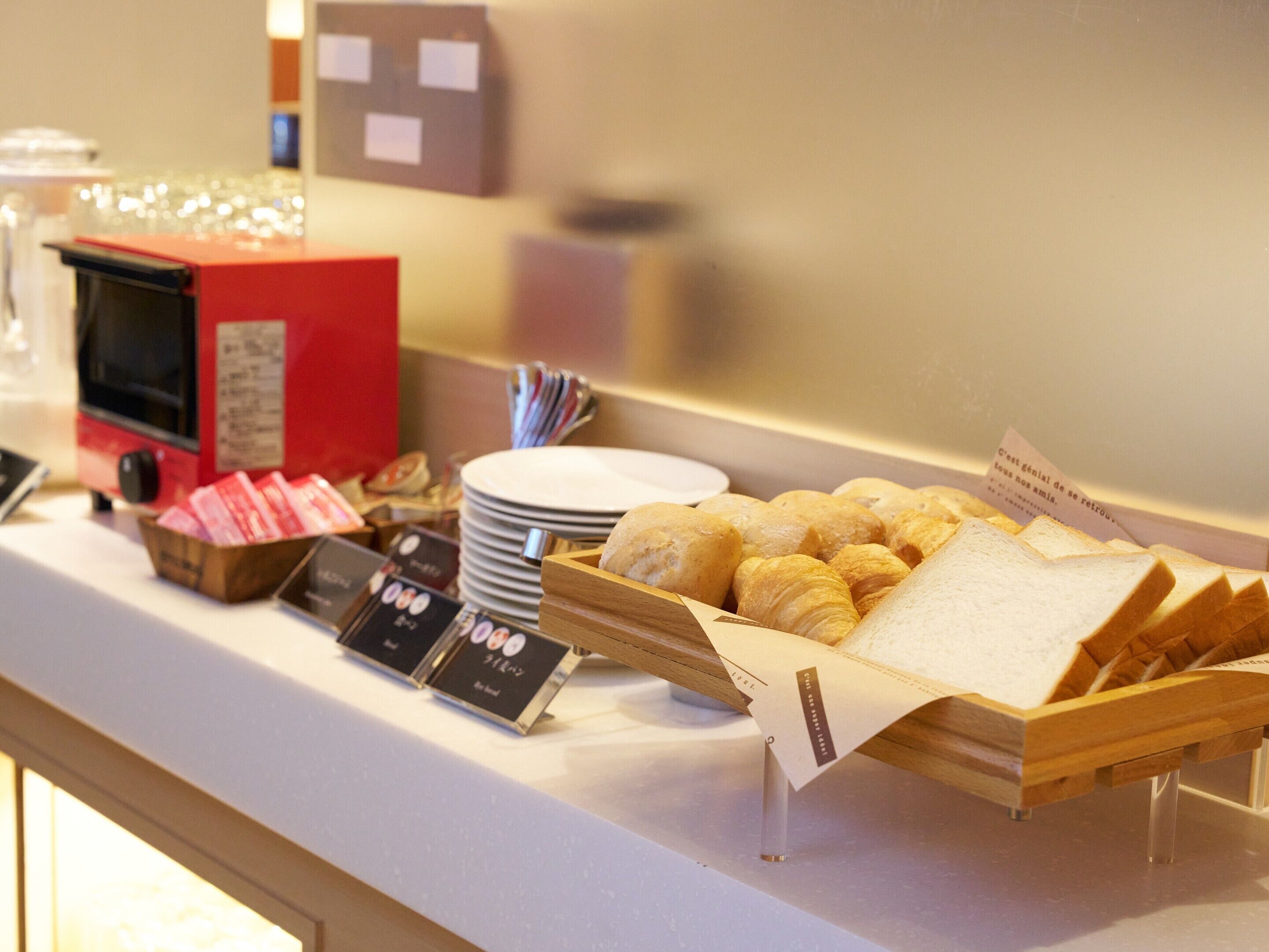 Balcão de buffet com pão, pastelaria e máquina de café.