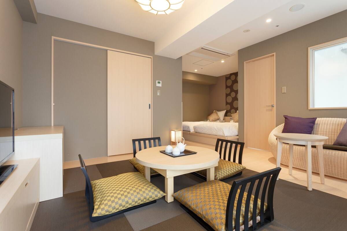 A hotel room with a dining area, a bed, and a sofa.