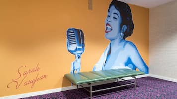 Una habitación con un mural de una mujer sosteniendo un micrófono, un banco y una cama.