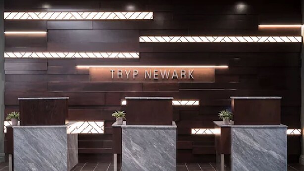 A reception area with a dark wood panel wall and three marble reception desks.