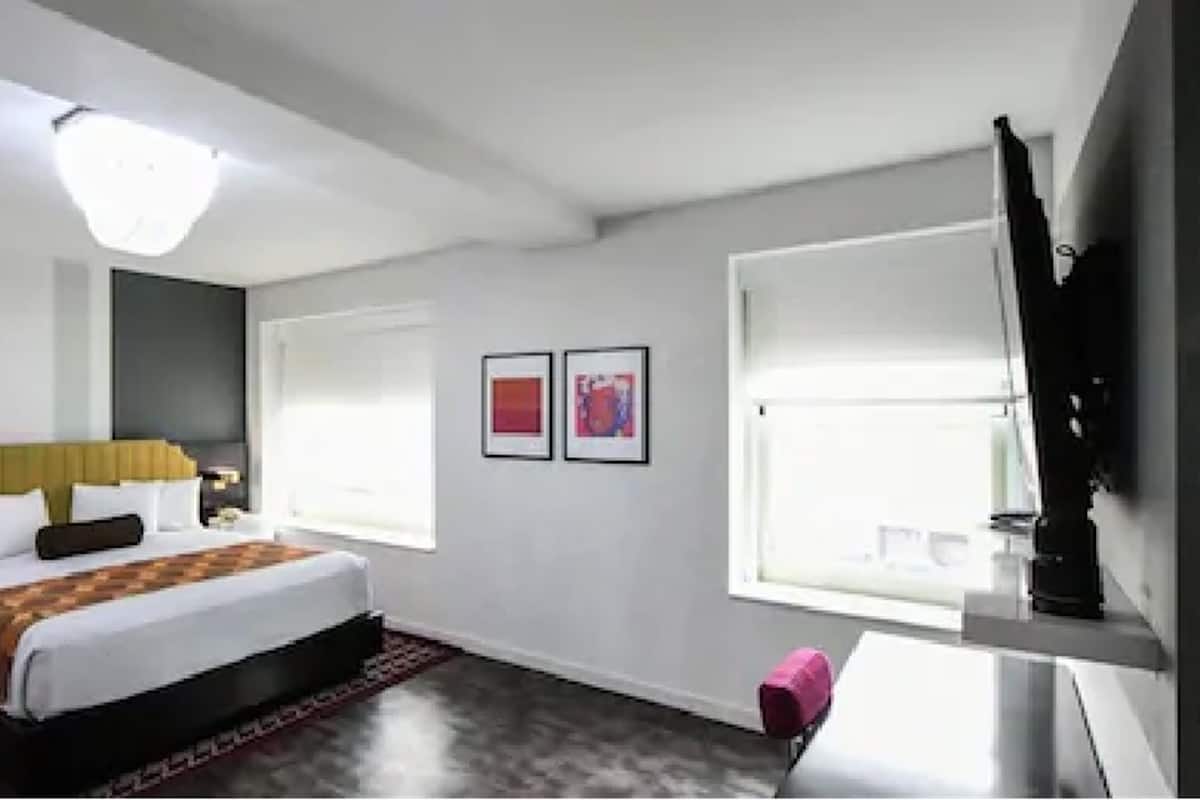 Une chambre d’hôtel moderne avec un grand lit, des tables de chevet, un bureau et une télévision.