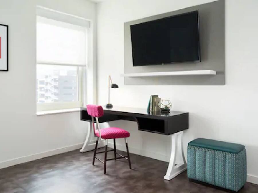 Um espaço de escritório moderno com uma mesa, cadeira e uma televisão fixada na parede.