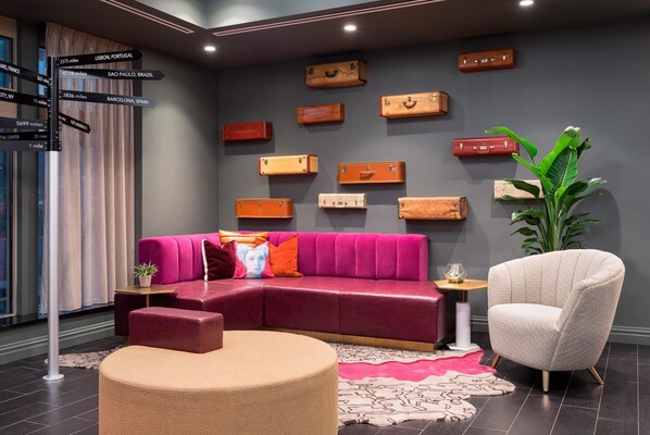 Una sala moderna con un sofá rojo, un sillón color beige y un cartel indicador.