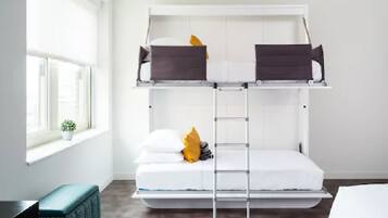 Ein Etagenbett mit einer Leiter, weiße Bettwäsche und ein kleiner Topf mit Pflanze am Fenster.
