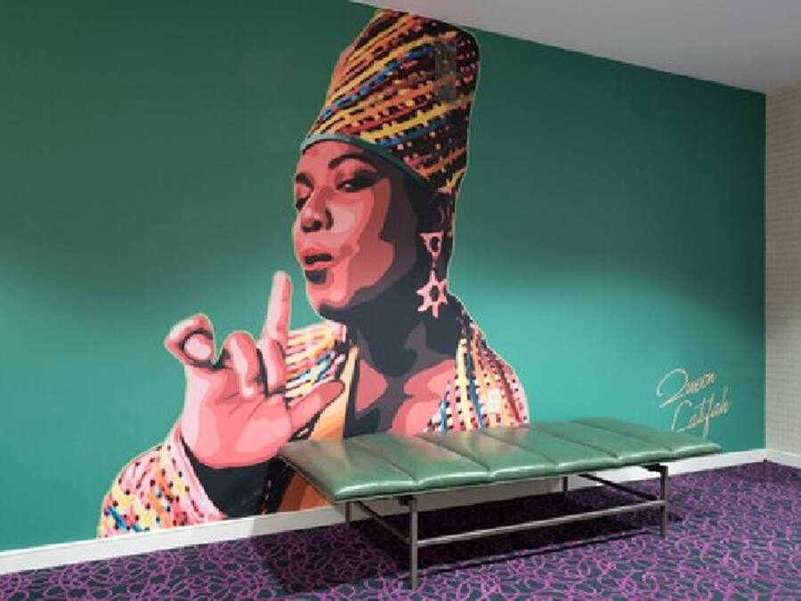 A room with a teal wall, a green bench, and a patterned carpet.