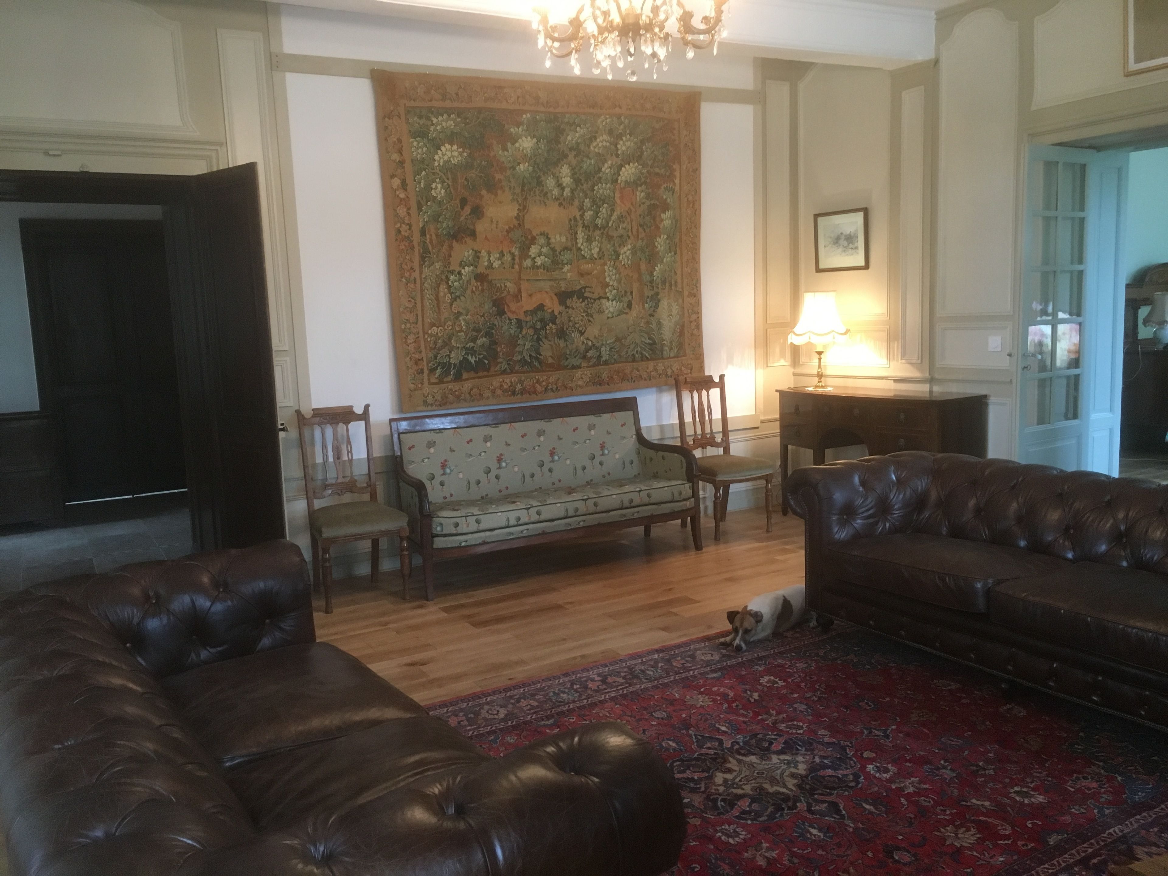 A living room with a large tapestry, two sofas, a wooden coffee table, and a rug.