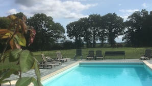 A swimming pool with lounge chairs and a view of trees in the background.