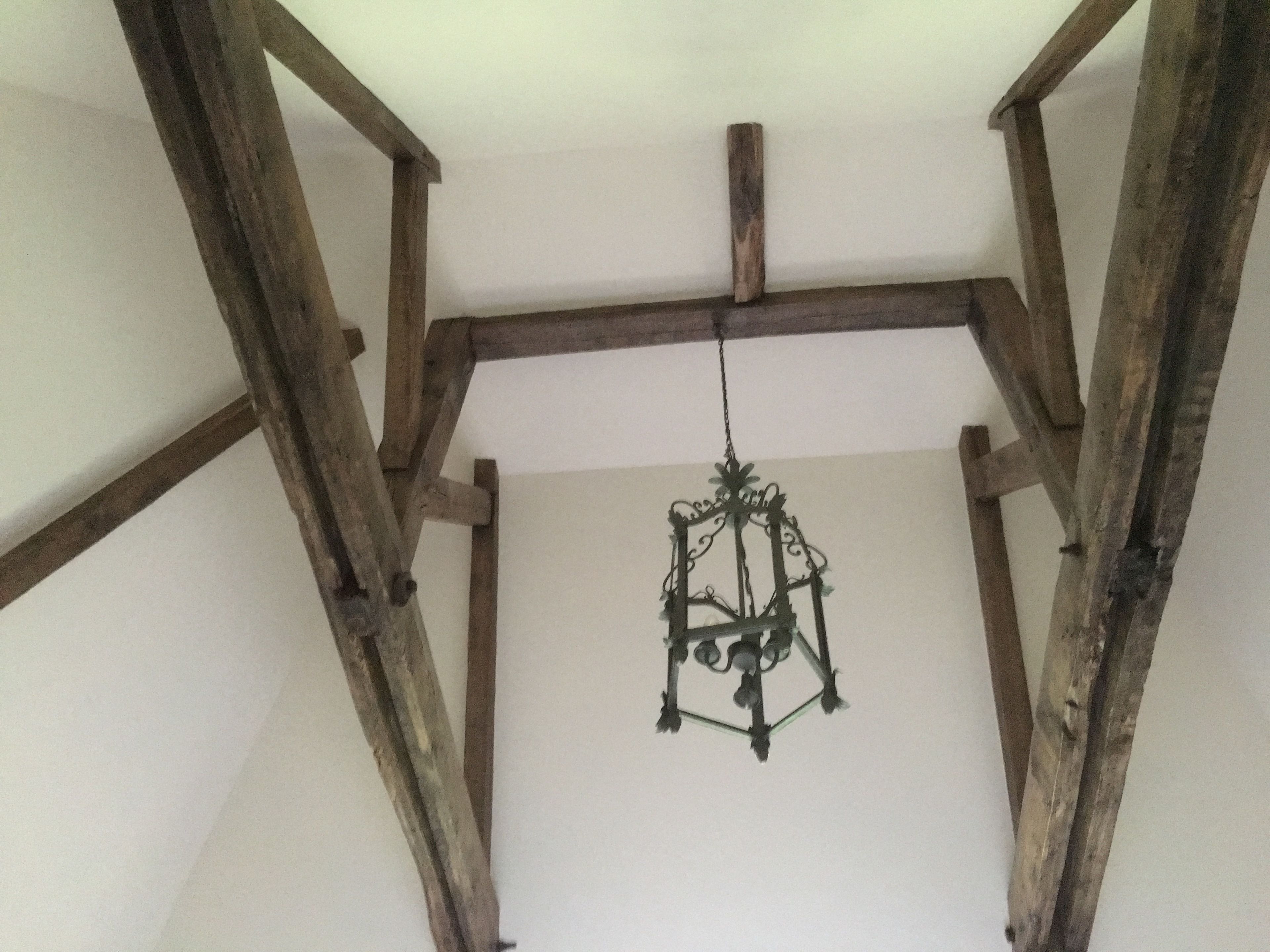 Una habitación con vigas de madera a la vista y una lámpara de araña colgante.