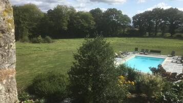 A swimming pool with lounge chairs and a grassy lawn.