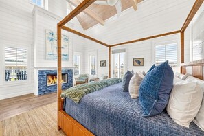 A spacious bedroom with a four-poster bed, a fireplace, and large windows. - Beach Home w/ Screen Porch near Beach Boardwalk, Pool+More Great Amenities (Port Aransas)