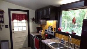 A compact kitchen with dark cabinets, a stove, and a double sink.