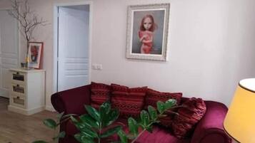 Una sala de estar con un sofá rojo, una planta y un cuadro en la pared.