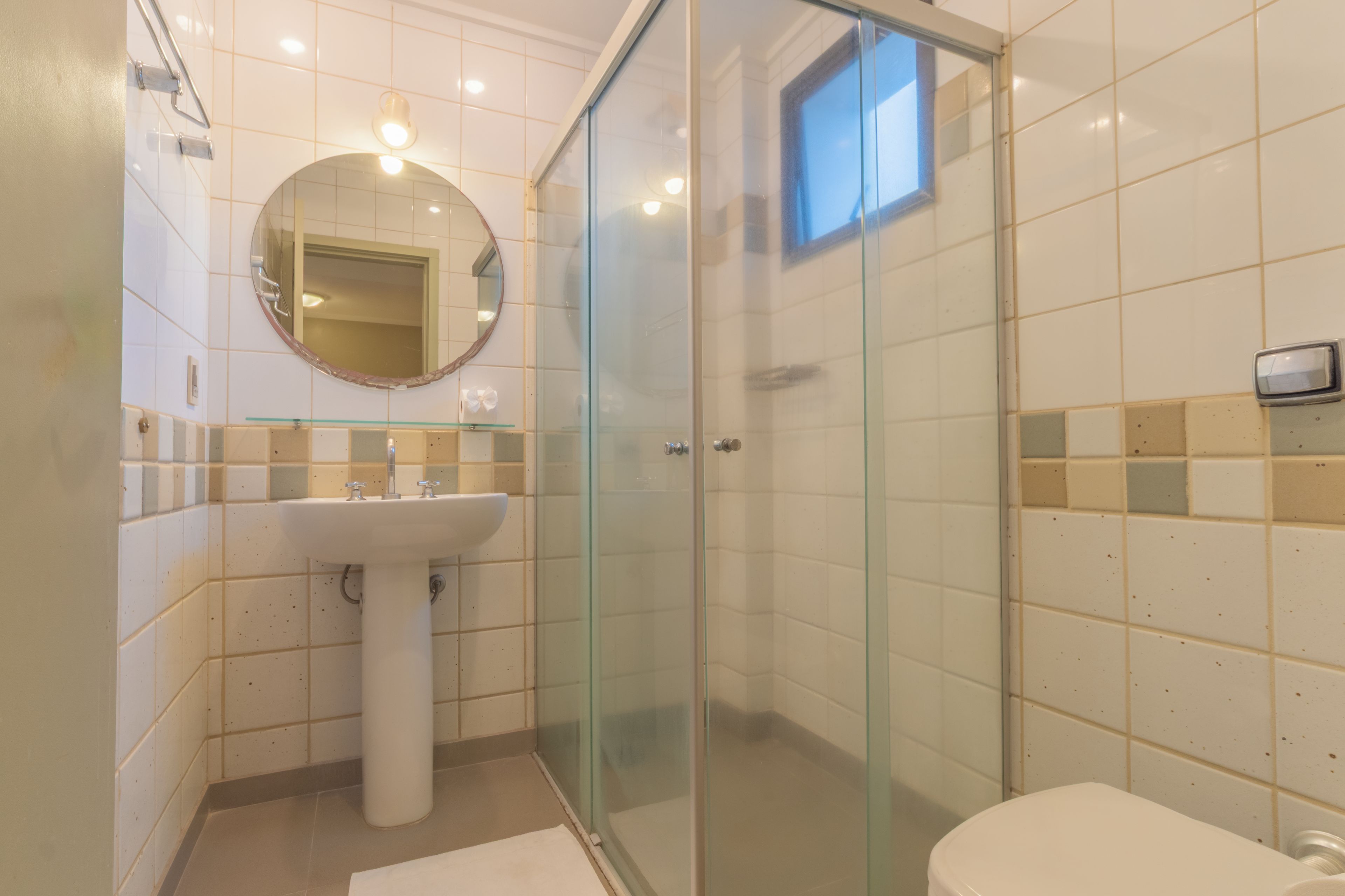 A bathroom with a glass-enclosed shower, a pedestal sink, and a toilet.