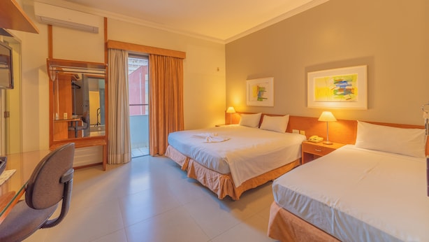 A hotel room with two beds, a desk, a chair, a bathroom, and a view of the outside. - Hotel Metrópolis (São José do Rio Preto)